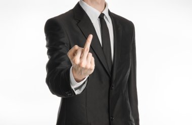 Businessman and gesture topic: a man in a black suit showing middle finger on an isolated white background in studio