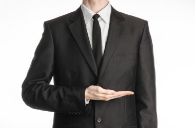 Businessman and gesture topic: a man in a black suit and tie holding his hand in front of him isolated on a white background in studio
