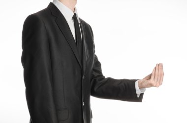 Businessman and gesture topic: a man in a black suit and tie holding his hand in front of him and shows a pinch gesture on an isolated white background in studio