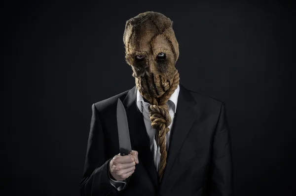 Tema Miedo y Halloween: un asesino brutal con una máscara sosteniendo un cuchillo sobre un fondo oscuro en el estudio —  Fotos de Stock
