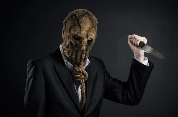 Fear and Halloween theme: a brutal killer in a mask holding a knife on a dark background in the studio — Stok fotoğraf