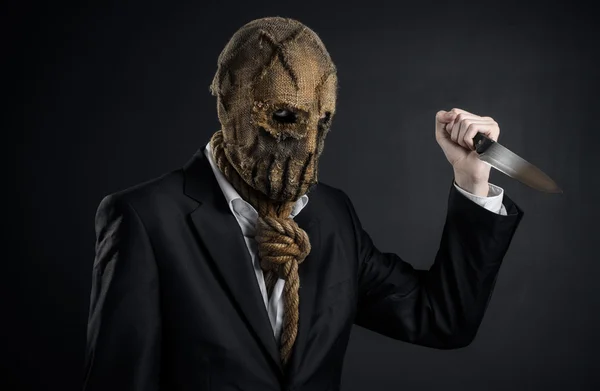 Tema Miedo y Halloween: un asesino brutal con una máscara sosteniendo un cuchillo sobre un fondo oscuro en el estudio —  Fotos de Stock