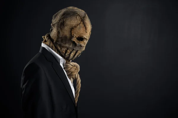 Fear and Halloween theme: a brutal killer in a mask on a dark background in the studio