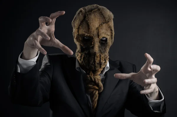 Fear and Halloween theme: a brutal killer in a mask on a dark background in the studio