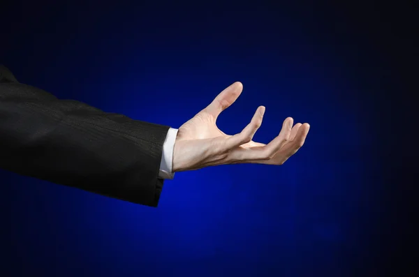 Businessman and gesture topic: a man in a black suit and white shirt showing hand gesture on an isolated dark blue background in studio — Stok fotoğraf