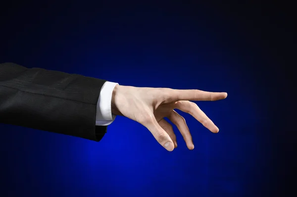 Предприниматель и тема жеста: человек в черном костюме и белой рубашке, показывающий жест рукой на изолированном темно-синем фоне в студии — стоковое фото