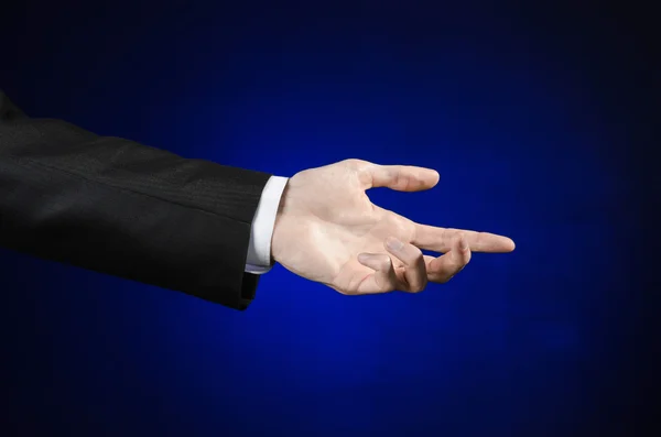 Businessman and gesture topic: a man in a black suit and white shirt showing hand gesture on an isolated dark blue background in studio — Stok fotoğraf