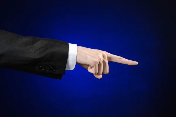 Businessman and gesture topic: a man in a black suit and white shirt showing hand gesture on an isolated dark blue background in studio — Stock Photo, Image