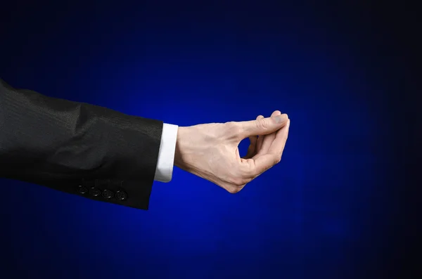 Businessman and gesture topic: a man in a black suit and white shirt showing hand gesture on an isolated dark blue background in studio — Stok fotoğraf