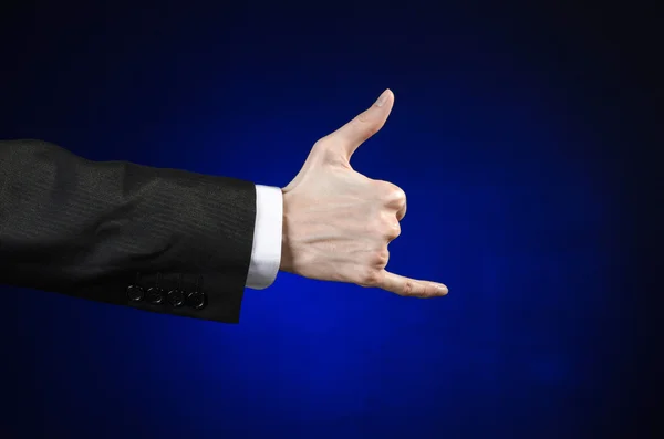 Бізнесмен і тема жесту: чоловік у чорному костюмі та білій сорочці, що показує жест рук на ізольованому темно-синьому фоні в студії — стокове фото