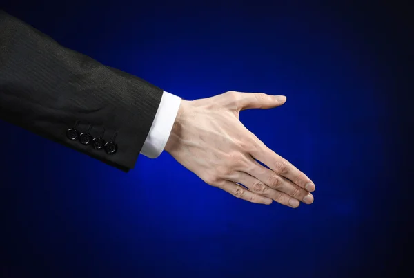 Businessman and gesture topic: a man in a black suit and white shirt showing hand gesture on an isolated dark blue background in studio — ストック写真