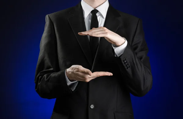 Hombre de negocios y tema de gestos: un hombre con traje negro y camisa blanca mostrando gestos con las manos sobre un fondo azul oscuro en estudio aislado —  Fotos de Stock