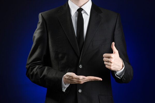 Предприниматель и тема жеста: человек в черном костюме и белой рубашке, показывающий жесты с руками на темно-синем фоне в изолированной студии
