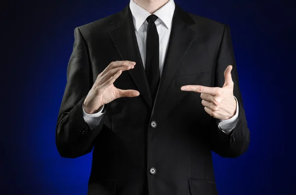 Businessman and gesture topic: a man in a black suit and white shirt showing gestures with hands on a dark blue background in studio isolated — Stock Photo, Image