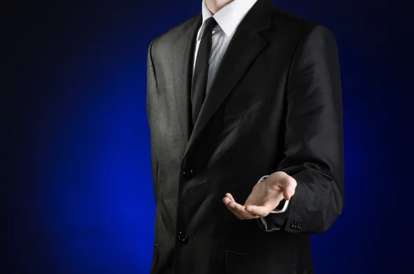 Businessman and gesture topic: a man in a black suit and white shirt holds up a hand against the dark blue isolated background in studio — 스톡 사진
