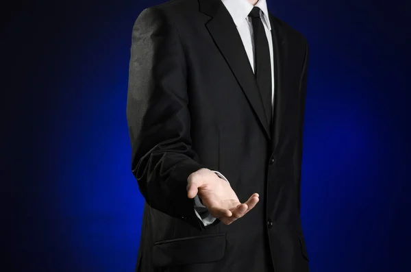 Businessman and gesture topic: a man in a black suit and white shirt holds up a hand against the dark blue isolated background in studio — Stockfoto