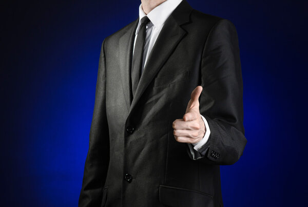 Предприниматель и тема жеста: человек в черном костюме и белой рубашке показывает руку вперед на темно-синем фоне в изолированной студии

