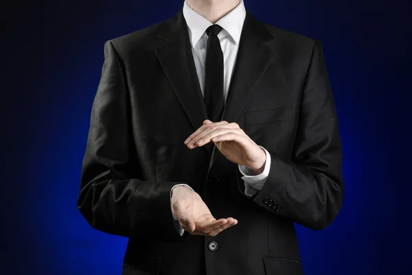 Businessman and gesture topic: a man in a black suit and white shirt showing gestures with hands on a dark blue background in studio isolated — 스톡 사진