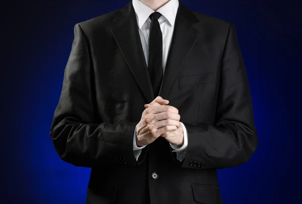 Businessman and gesture topic: a man in a black suit and white shirt holds her hands together in front of you and prays, meditates on a dark blue background in studio isolated — Stock Photo, Image