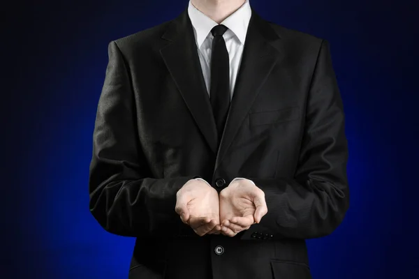 Businessman and gesture topic: a man in a black suit and white shirt showing gestures with hands on a dark blue background in studio isolated — 图库照片