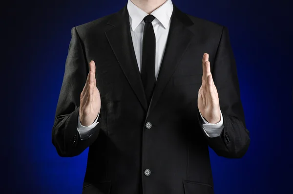 Бізнесмен і тема жестів: чоловік у чорному костюмі і біла сорочка, що показує жести руками на темно-синьому фоні в студії ізольовані — стокове фото