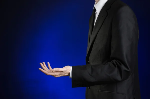 Businessman and gesture topic: a man in a black suit and white shirt showing gestures with hands on a dark blue background in studio isolated — 스톡 사진