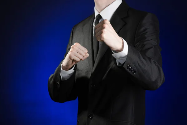 Tópico de homem de negócios e gesto: um homem de terno preto e camisa branca segurando seus punhos na frente dele em um fundo azul escuro no estúdio isolado — Fotografia de Stock
