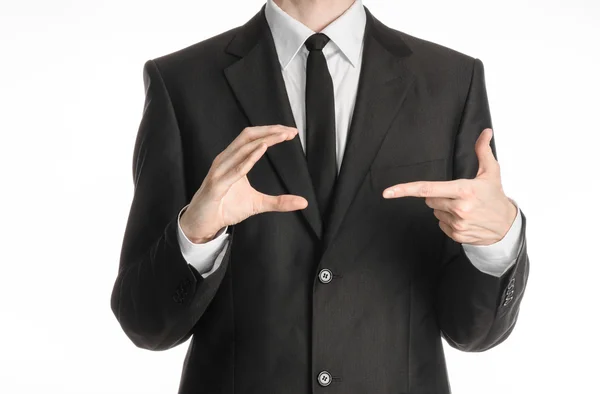 Tópico de homem de negócios e gesto: um homem de terno preto e gravata segura sua mão direita e aponta para sua esquerda isolada em fundo branco no estúdio — Fotografia de Stock