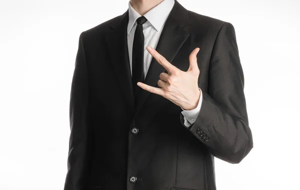 Businessman and gesture topic: a man in a black suit with a tie showing rock hand gesture on an isolated white background in studio — ストック写真