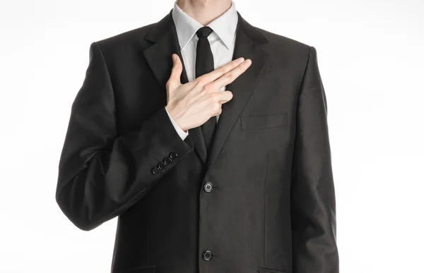 Hombre de negocios y tema del gesto: un hombre con un traje negro con una corbata puso su mano sobre su pecho con un gesto en forma de pistola aislada sobre fondo blanco en el estudio — Foto de Stock