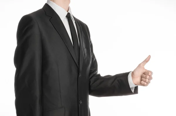 Businessman and gesture topic: a man in a black suit and tie holding his hand in front of him and shows thumb up isolated on white background in studio — ストック写真