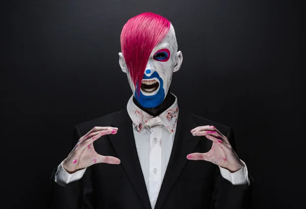 Clown e tema Halloween: clown spaventoso con capelli rosa in giacca nera su sfondo scuro in studio — Foto Stock