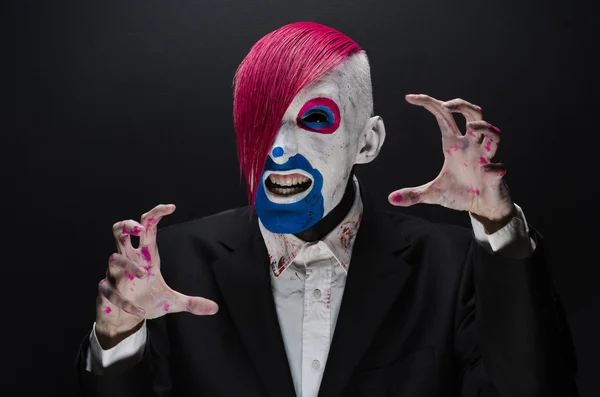 Clown and Halloween theme: Scary clown with pink hair in a black jacket on a dark background in the studio — Stok fotoğraf