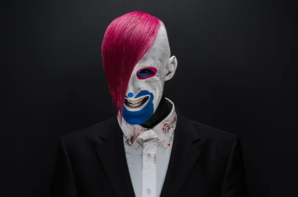 Clown and Halloween theme: Scary clown with pink hair in a black jacket on a dark background in the studio — 图库照片