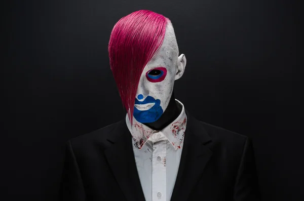 Clown e tema Halloween: clown spaventoso con capelli rosa in giacca nera su sfondo scuro in studio — Foto Stock