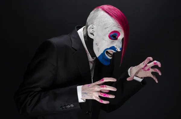 Clown et Halloween thème : Clown effrayant avec les cheveux roses dans une veste noire sur un fond sombre dans le studio — Photo