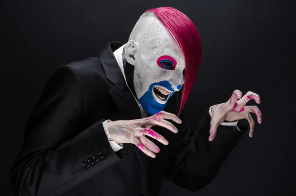 Clown and Halloween theme: Scary clown with pink hair in a black jacket on a dark background in the studio — Stockfoto