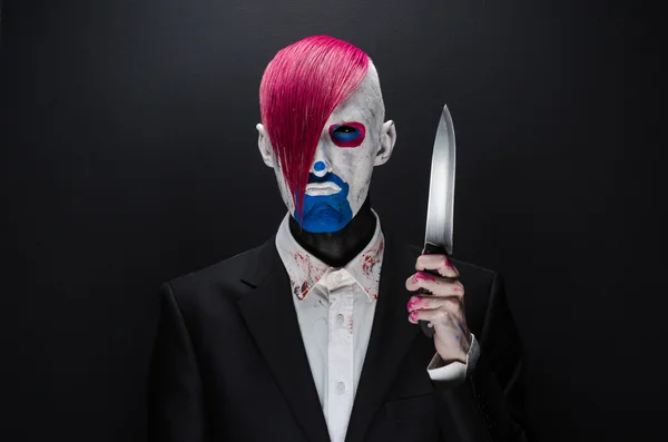 Clown and Halloween theme: Scary clown with pink hair in a black suit with a knife in his hand on a dark background in the studio — Φωτογραφία Αρχείου