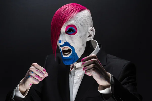 Clown and Halloween theme: Scary clown with pink hair in a black jacket on a dark background in the studio — Stockfoto