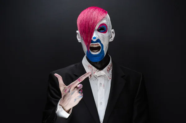 Clown and Halloween theme: Scary clown with pink hair in a black jacket on a dark background in the studio — 图库照片