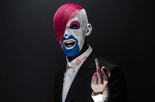 Clown and Halloween theme: Scary clown with pink hair in a black jacket on a dark background in the studio — 图库照片