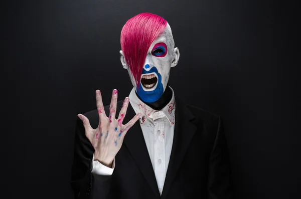 Clown and Halloween theme: Scary clown with pink hair in a black jacket on a dark background in the studio — Stok fotoğraf