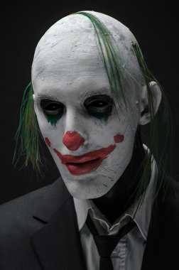 Korkunç palyaço ve Halloween Tema: izole stüdyoda karanlık bir arka plan üzerinde siyah elbiseli çılgın korkunç yeşil palyaço