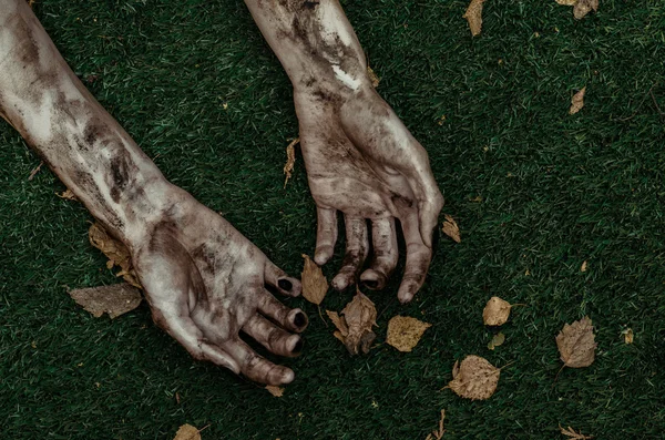 Horror en Halloween thema: verschrikkelijke zombie handen vuil met zwarte nagels liggen op het groene gras, de walking dead Apocalyps, top weergave — Stockfoto