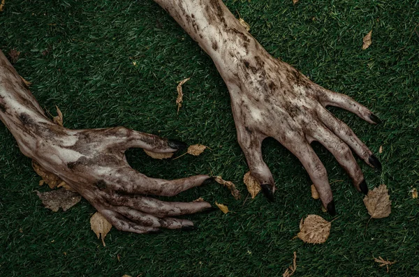 Terror y Halloween tema: terribles manos zombi sucio con uñas negras se encuentran en la hierba verde, el apocalipsis muertos vivientes, vista superior —  Fotos de Stock