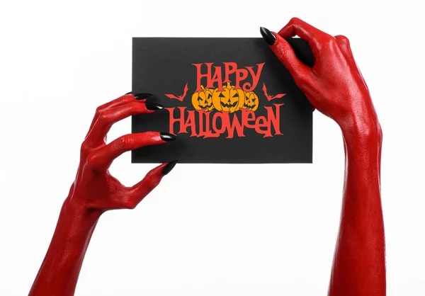 Postcard and Happy Halloween theme: red devil hand with black nails holding a paper card with the words Happy Halloween on a white isolated background in studio — Stok fotoğraf