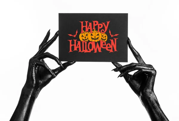 Postal y tema Feliz Halloween: mano negra de la muerte sosteniendo una tarjeta de papel con las palabras Feliz Halloween sobre un fondo blanco aislado en el estudio —  Fotos de Stock