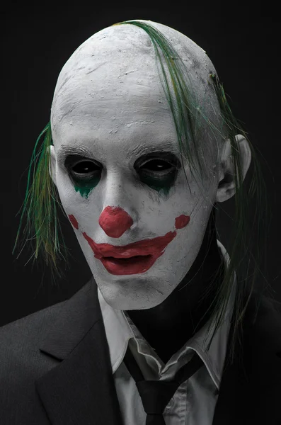 Ужасный клоун и Хэллоуин тема: Сумасшедший ужасный зеленый клоун в черном костюме изолирован на темном фоне в студии — стоковое фото