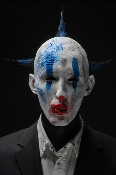 Schrecklicher Clown und Halloween-Thema: verrückter schrecklicher blauer Clown im schwarzen Anzug isoliert auf dunklem Hintergrund im Studio — Stockfoto