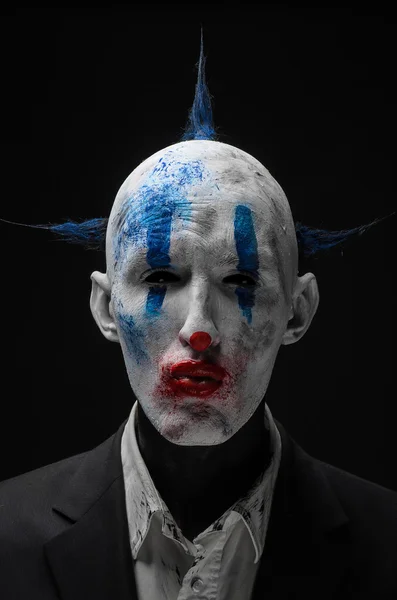 Schrecklicher Clown und Halloween-Thema: verrückter schrecklicher blauer Clown im schwarzen Anzug isoliert auf dunklem Hintergrund im Studio — Stockfoto